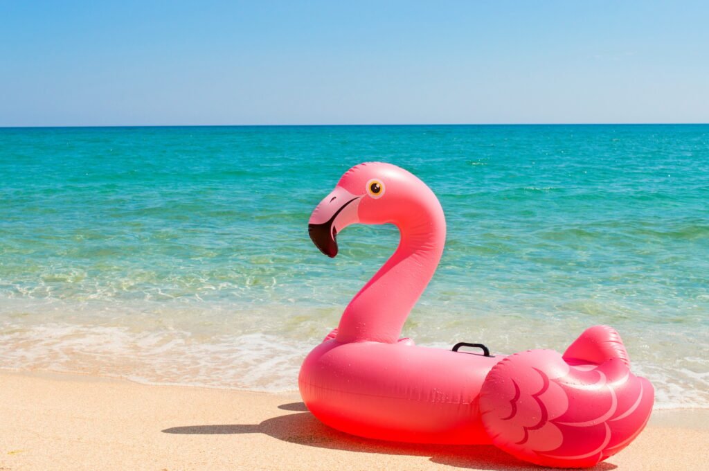 Pink inflatable mattress Flamingo on the beach close-up. The concept of tourism, travel, vacations.